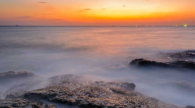Long exposure seascape during blue hour sunset with rocks as foreground. Nature composition.